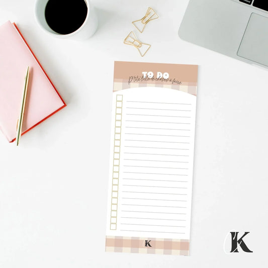 Retro checkered to-do list notepad on white desk with pen, notebook, and laptop