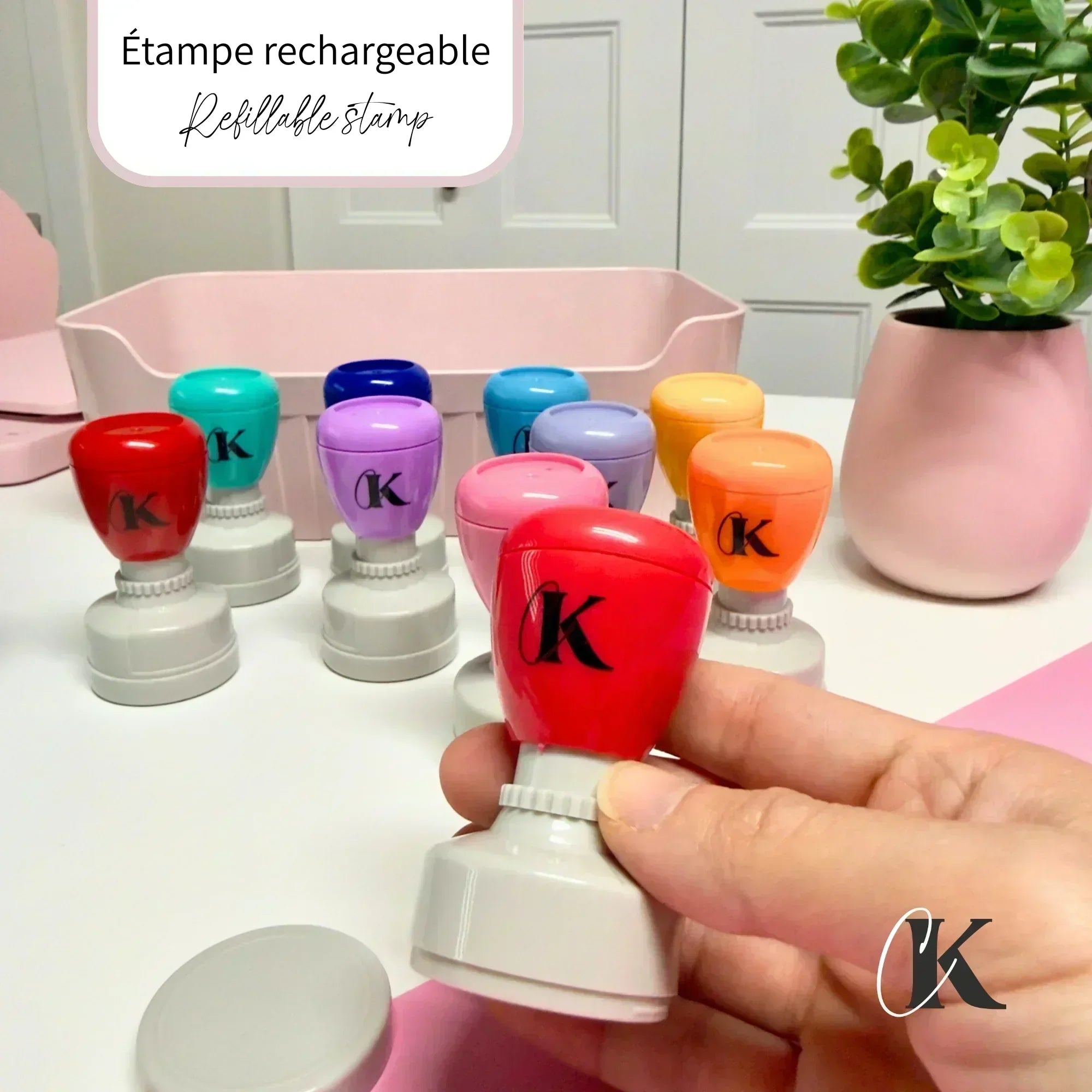 Colorful refillable stamps with gray bases on a white desk, one held in hand
